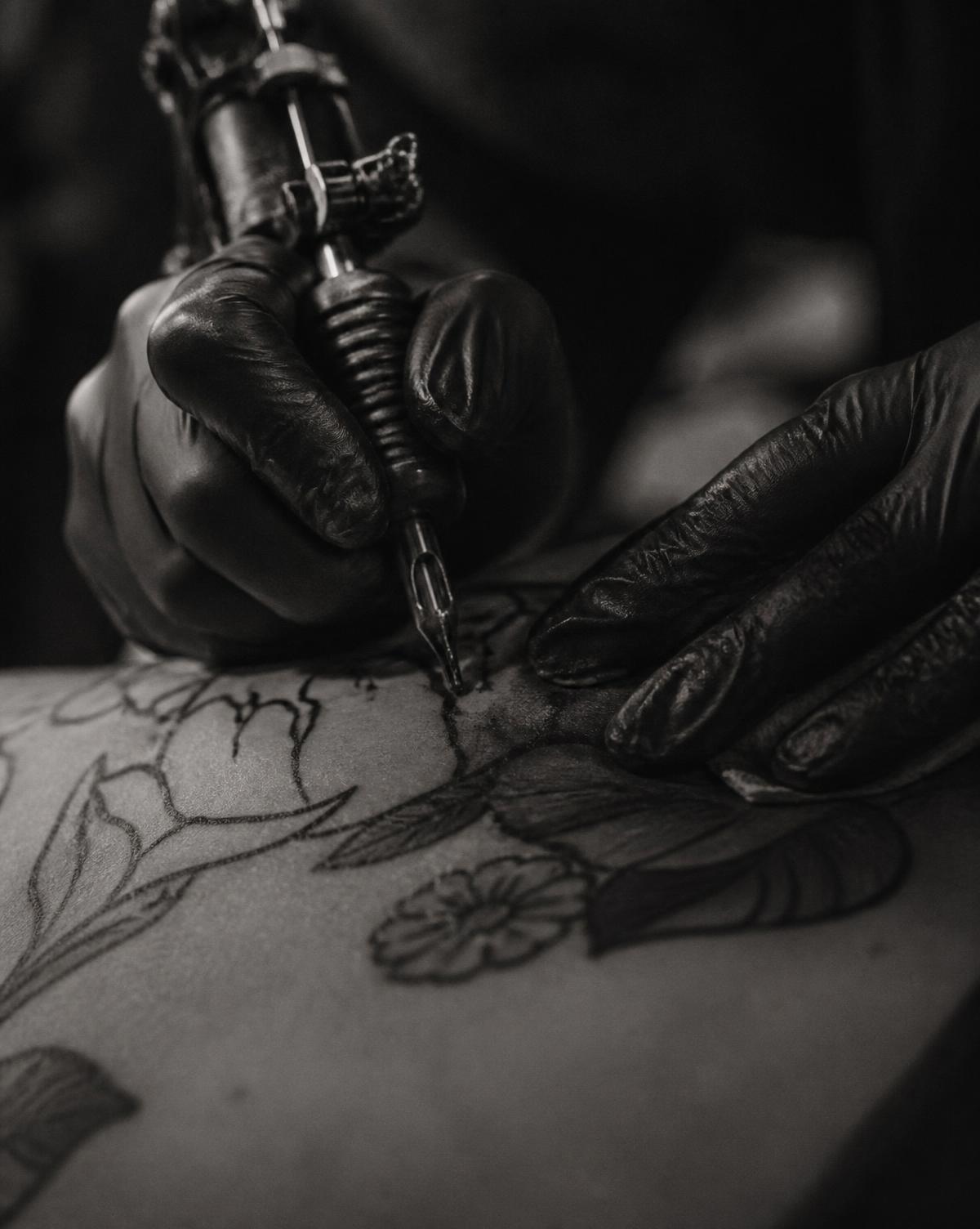 Kevin tattooing a fine line botanical piece